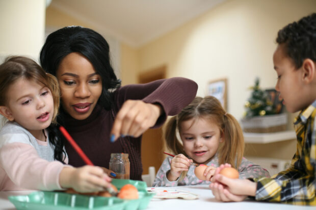 Childminder with three children doing arts and crafts