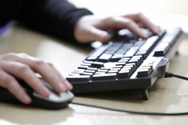 A person's hands using a mouse and keyboard