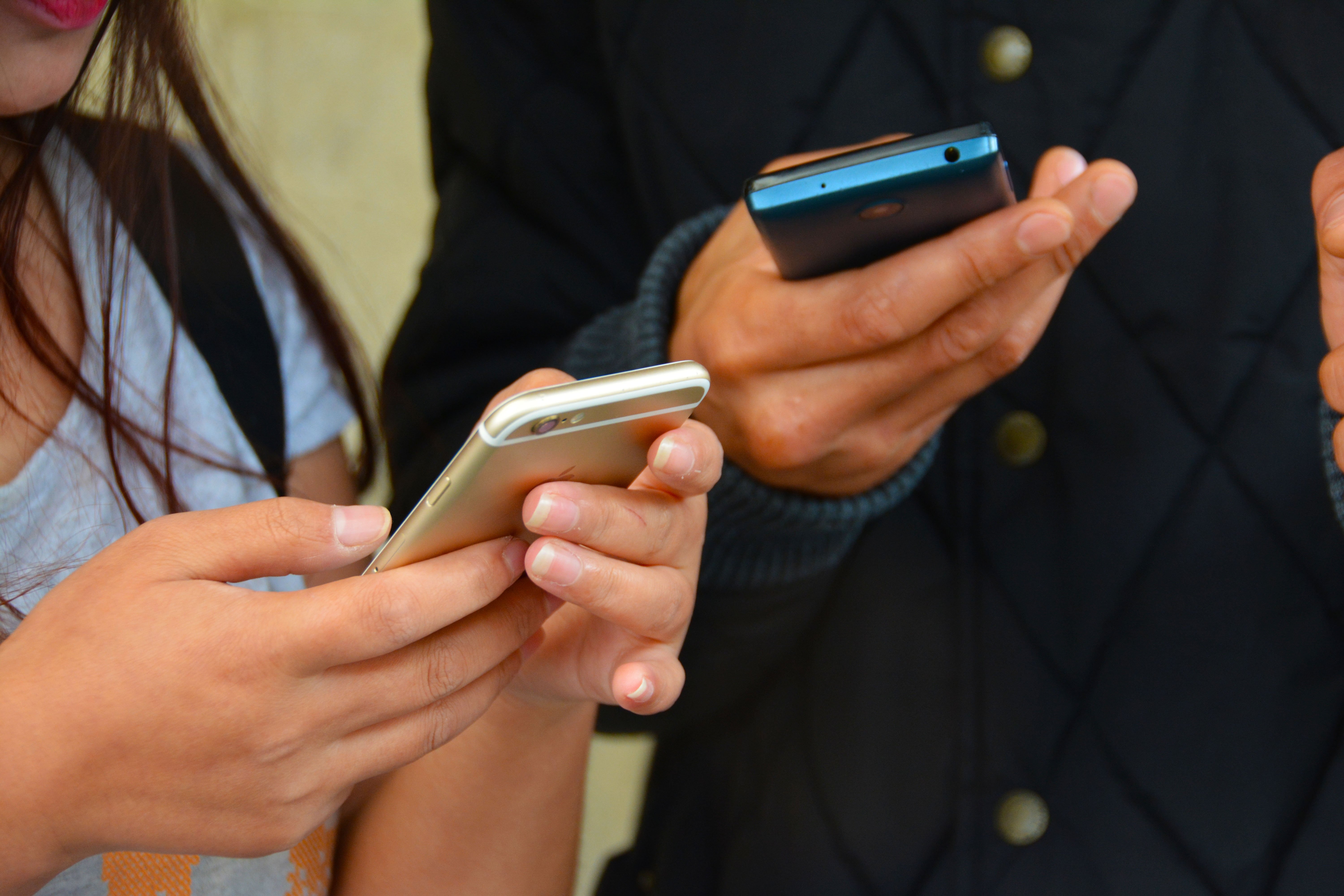 Two people holding and looking at their mobile phones.